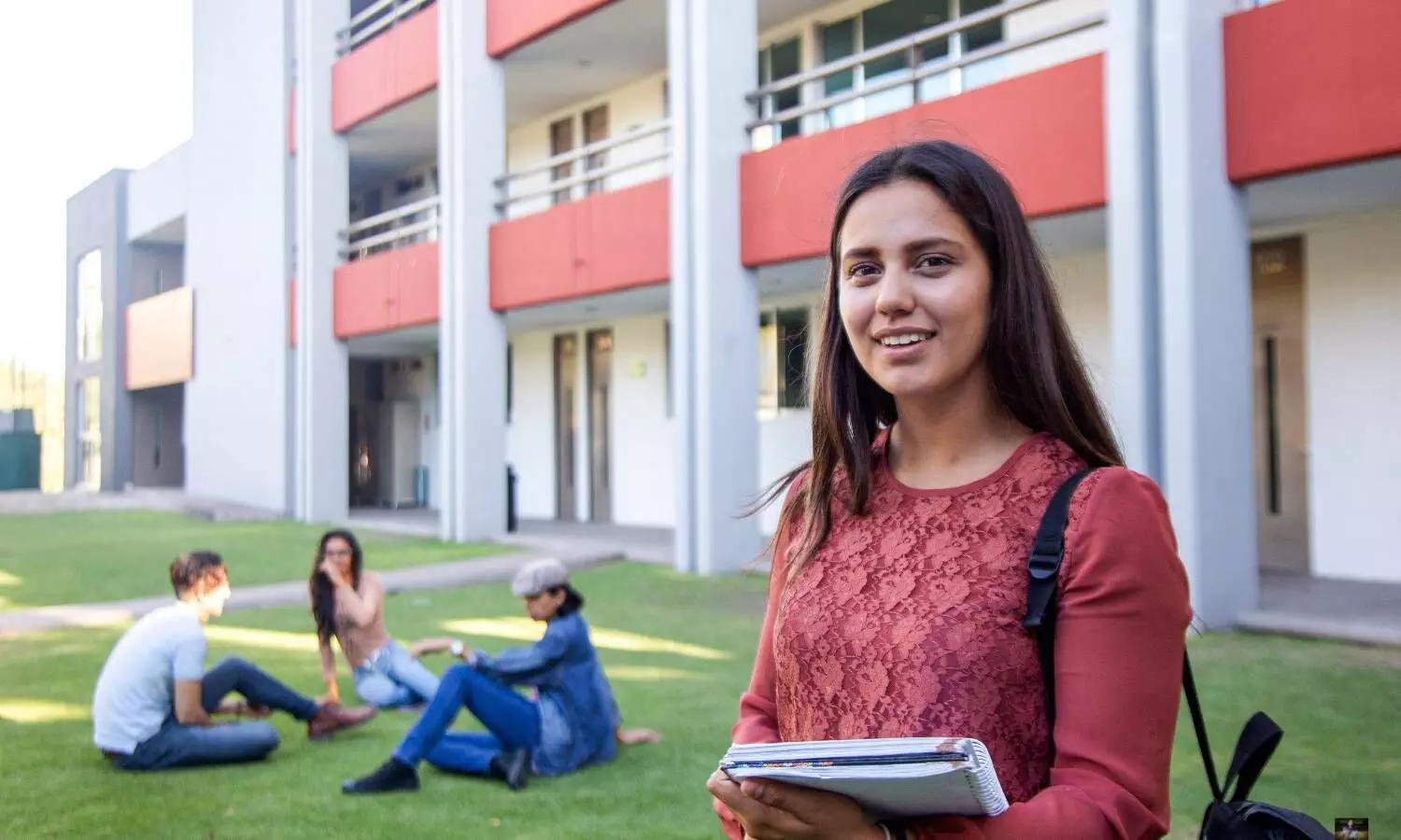 a girl smiling three students sitting in the lawn