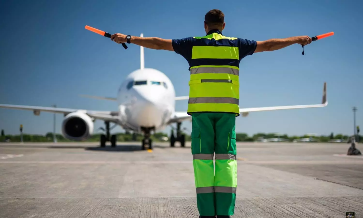 a ground handling staff guiding a aeroplane