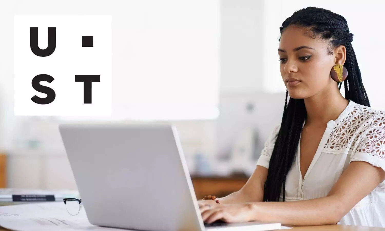 lady working on computer and ust logo